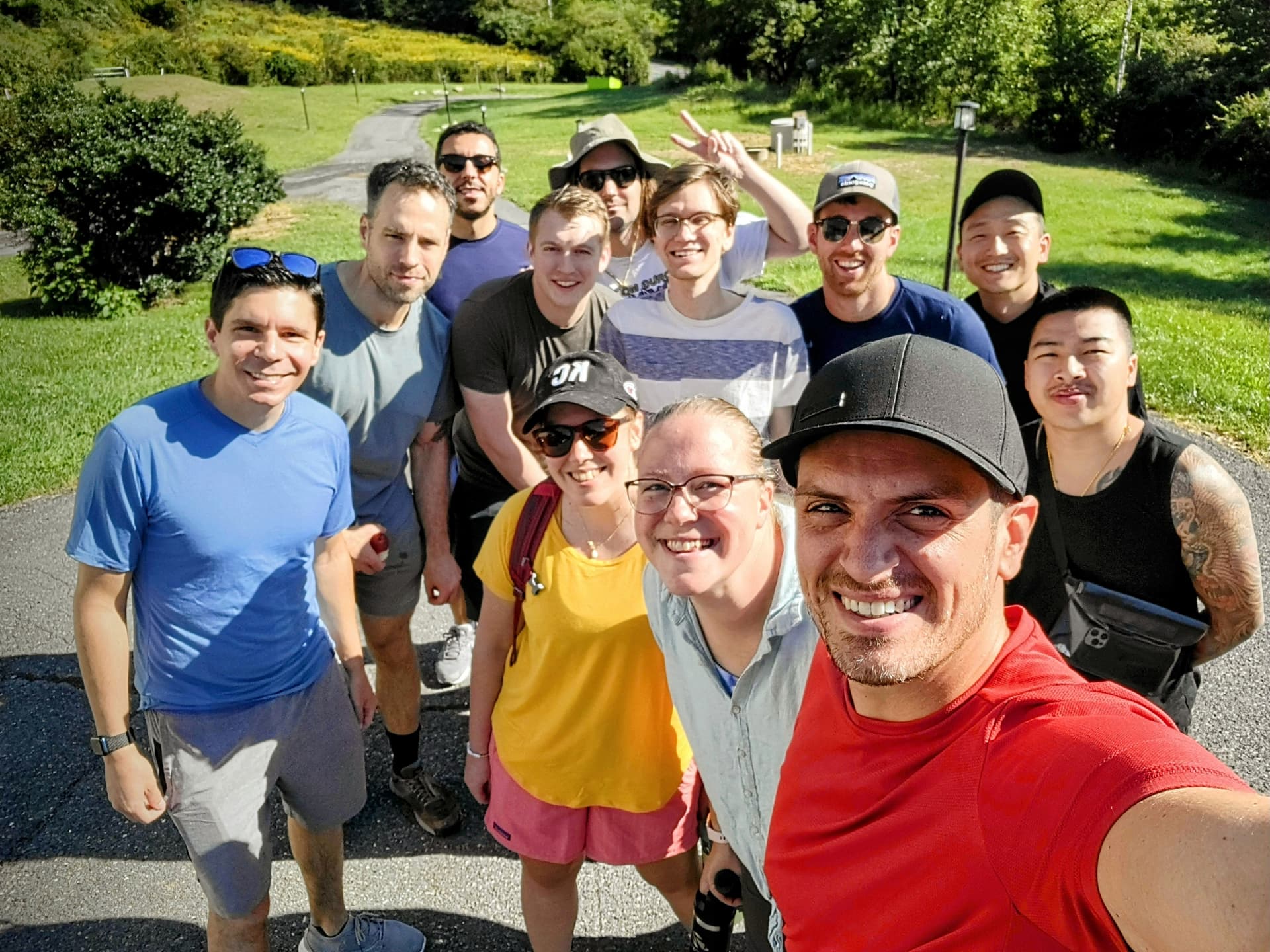 12 AuthZed employees smiling outside on a driveway surrounded by grass